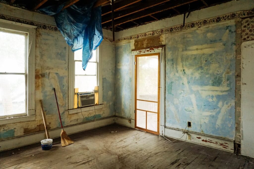 An empty room in an abandoned house with peeling walls and construction tools.